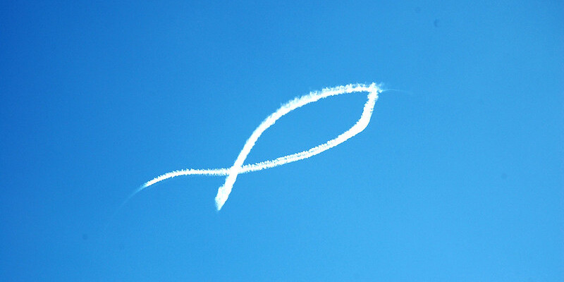 Christus-Symbol als weiße Lichtspur im blauen Himmel