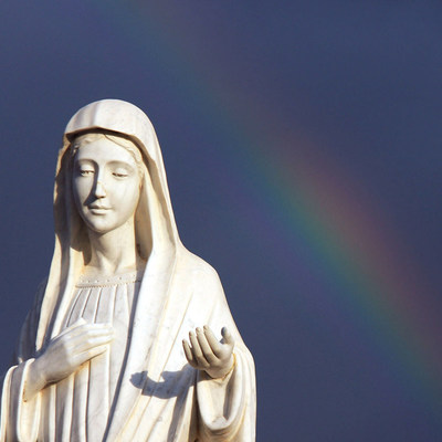 Bis zu einer Million Pilger besuchen jährlich den Wallfahrtsort Medjugorje. Bild: Marienstatue vor einem Regenbogen.