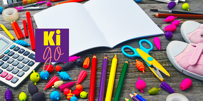 Ein Schulheft mit Stiften, Rechner, Schere und weiteren Schulsachen rundherum.