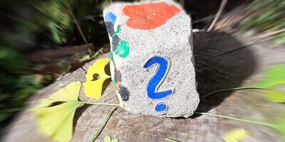 Granitquader mit blauem Fragezeichen vorne und rotem Herz oben, Umgebung unscharf